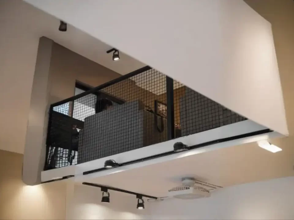 Mezanino interno com proteção de tela metálica expandida preta, garantindo segurança sem bloquear a visão ou ventilação.