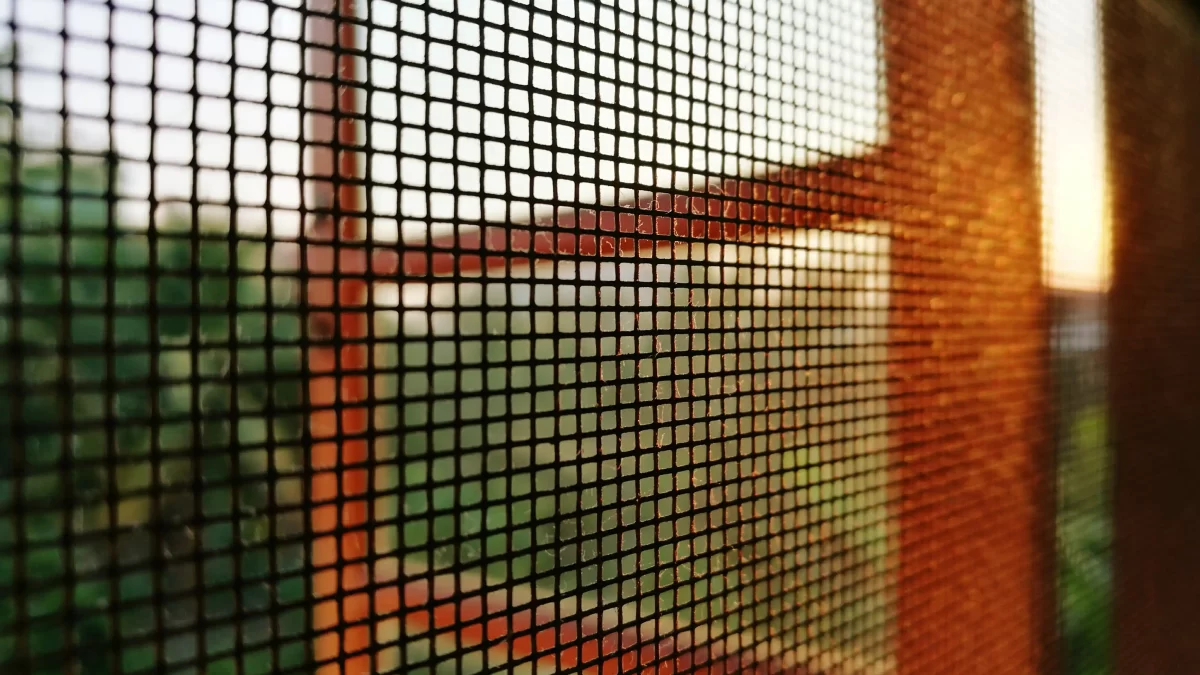 Tela metálica com malha quadrada instalada em janela, permitindo ventilação e entrada de luz natural